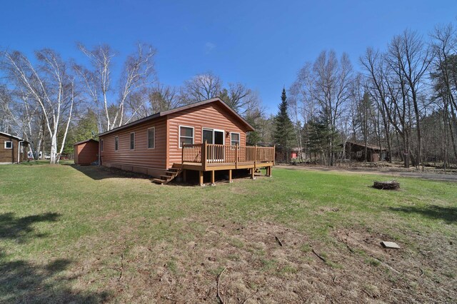 back of house featuring a lawn, a deck, and log veneer siding