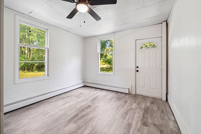 unfurnished room featuring ceiling fan, a baseboard heating unit, a paneled ceiling, and light wood-type flooring