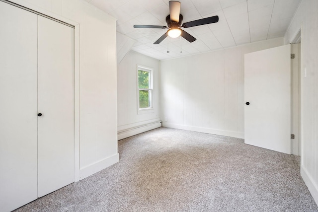 unfurnished bedroom featuring ceiling fan, carpet flooring, a closet, and a baseboard heating unit