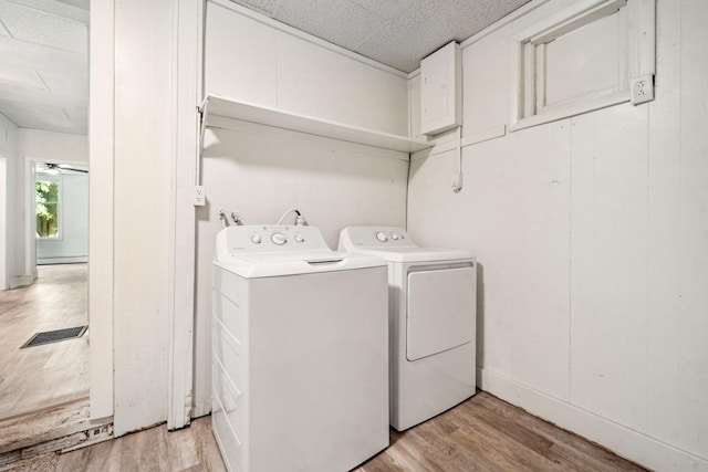 laundry area with ceiling fan, a textured ceiling, independent washer and dryer, and light hardwood / wood-style floors