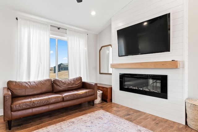 living room with a large fireplace, lofted ceiling, and hardwood / wood-style floors