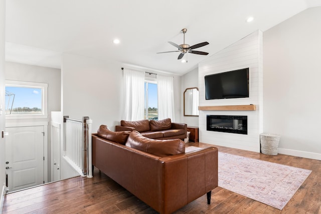 living room featuring ceiling fan, wood-type flooring, a large fireplace, and plenty of natural light