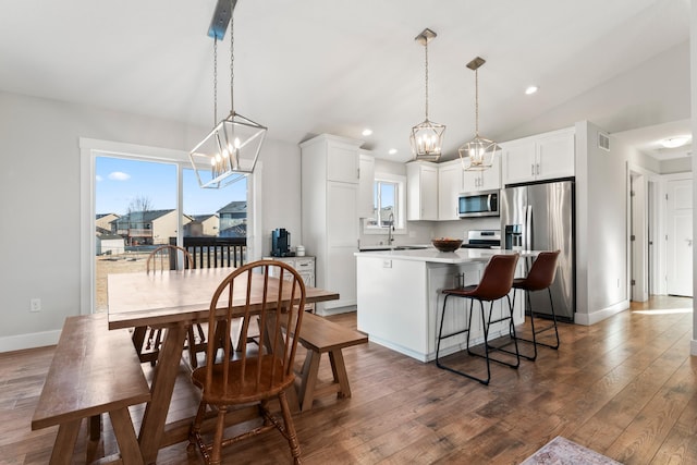 dining space with lofted ceiling, dark hardwood / wood-style flooring, a wealth of natural light, and a notable chandelier