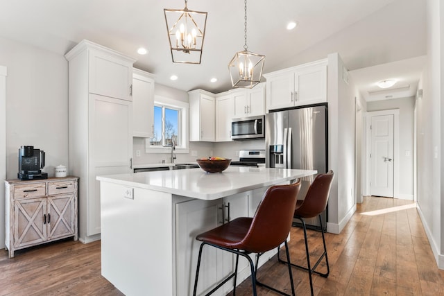 kitchen featuring pendant lighting, a center island, white cabinetry, stainless steel appliances, and a kitchen breakfast bar