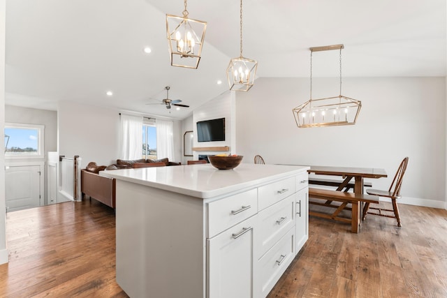 kitchen featuring white cabinetry, ceiling fan, dark wood-type flooring, hanging light fixtures, and a kitchen island