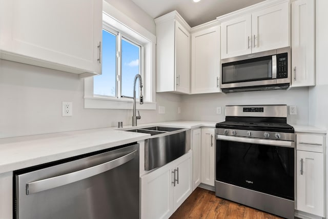 kitchen with dark wood-type flooring, appliances with stainless steel finishes, white cabinetry, and sink