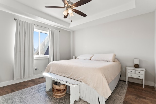 bedroom featuring a raised ceiling, ceiling fan, and dark hardwood / wood-style floors