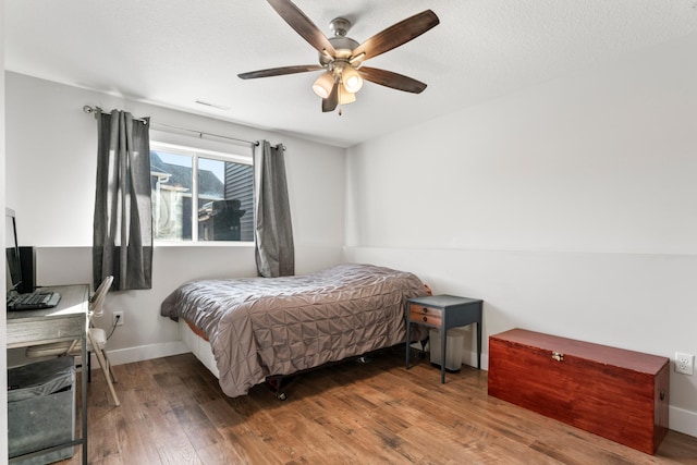 bedroom featuring ceiling fan, a textured ceiling, and dark hardwood / wood-style flooring