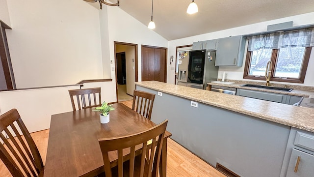 kitchen with appliances with stainless steel finishes, decorative light fixtures, light hardwood / wood-style floors, sink, and gray cabinetry