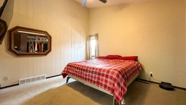 bedroom featuring ceiling fan, carpet, and wooden walls