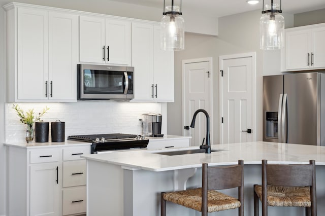 kitchen featuring a breakfast bar, white cabinetry, appliances with stainless steel finishes, and an island with sink