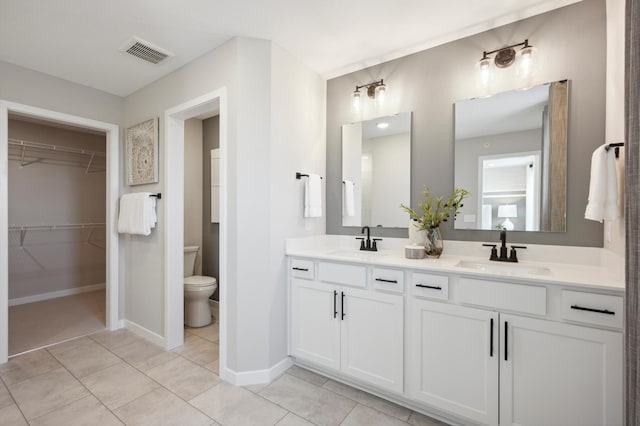 bathroom with toilet, vanity, and tile patterned floors