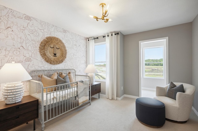 bedroom featuring light carpet, a notable chandelier, a crib, and multiple windows