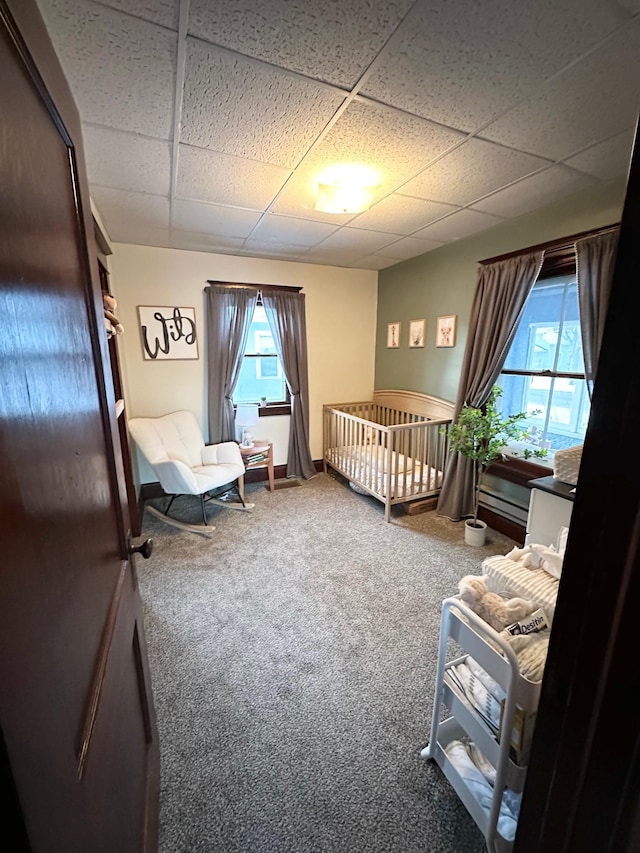 bedroom featuring carpet, refrigerator, a drop ceiling, and a crib