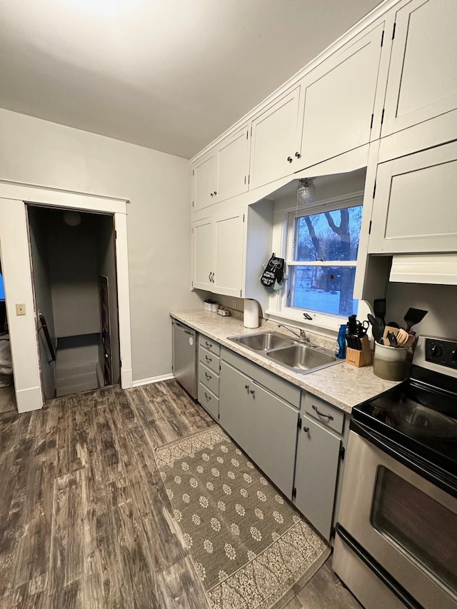 kitchen with white cabinetry, appliances with stainless steel finishes, dark hardwood / wood-style floors, and sink