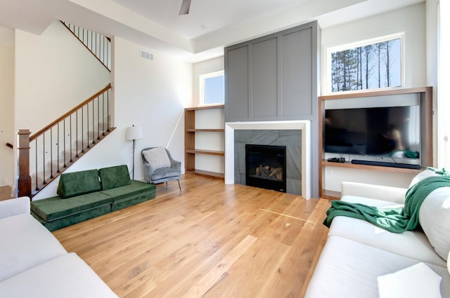 living room with ceiling fan, a tile fireplace, and light wood-type flooring