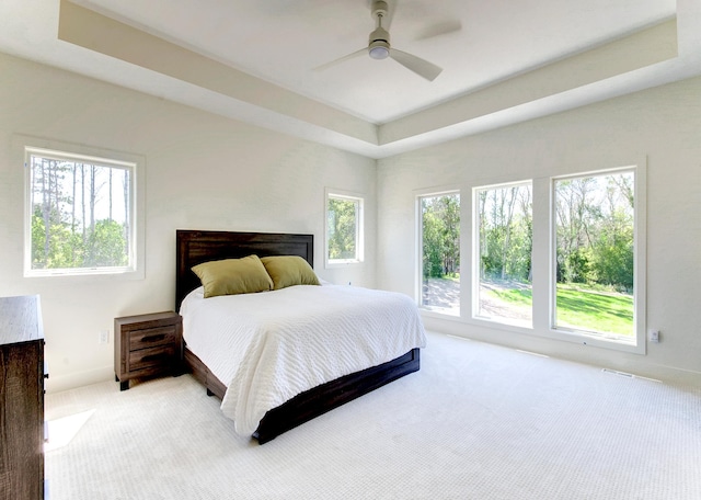 carpeted bedroom with ceiling fan and a raised ceiling