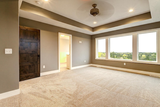 unfurnished bedroom with carpet flooring, connected bathroom, ceiling fan, and a raised ceiling