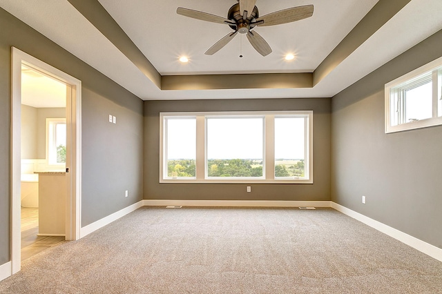 carpeted empty room with ceiling fan and a raised ceiling