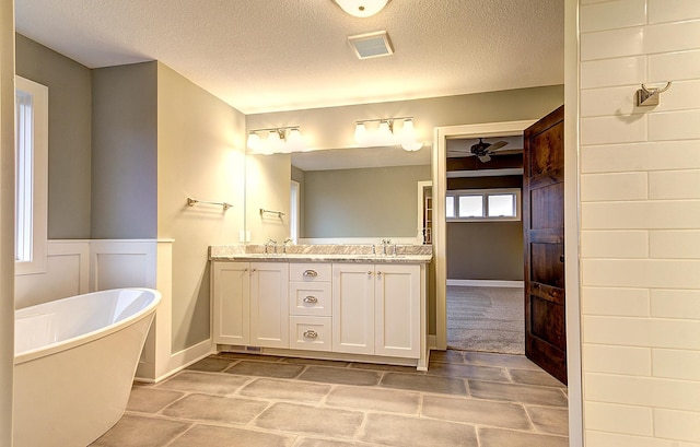 bathroom featuring vanity, a tub, and a textured ceiling