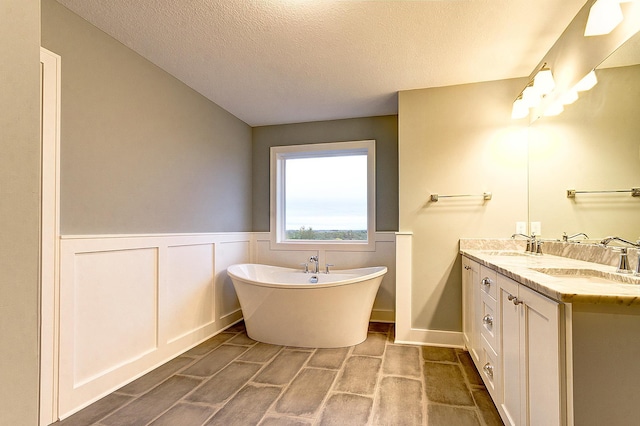 bathroom featuring a textured ceiling, a bath, and vanity