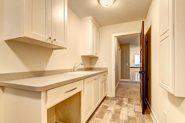 kitchen featuring sink, white cabinetry, and a textured ceiling