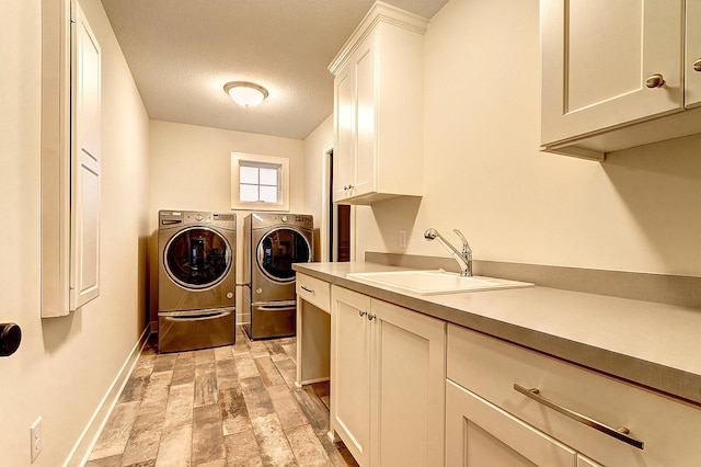 laundry area with sink, cabinets, a textured ceiling, and washer and clothes dryer