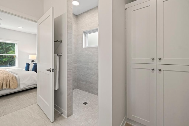 bathroom with a tile shower and a healthy amount of sunlight