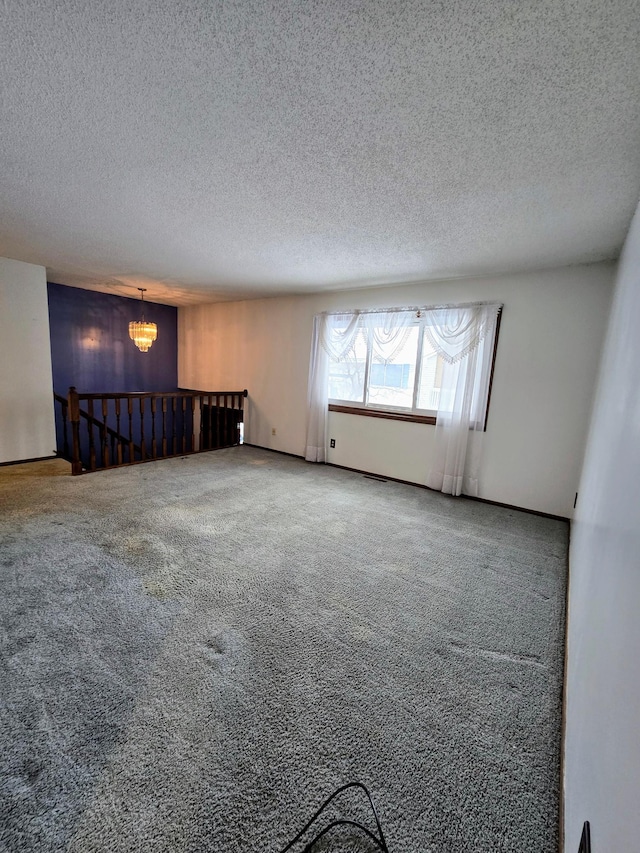 spare room featuring a textured ceiling, a chandelier, and carpet