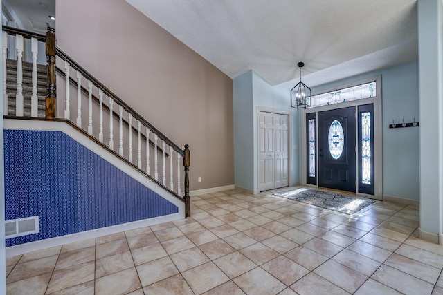 entryway with a chandelier, stairway, tile patterned flooring, and baseboards