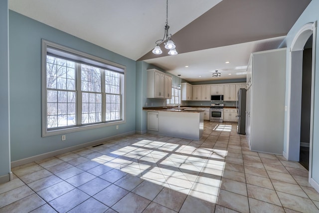 kitchen with light tile patterned flooring, a peninsula, baseboards, appliances with stainless steel finishes, and dark countertops