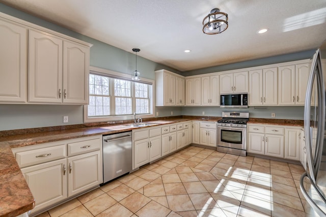 kitchen with stainless steel appliances, hanging light fixtures, light tile patterned flooring, and a sink