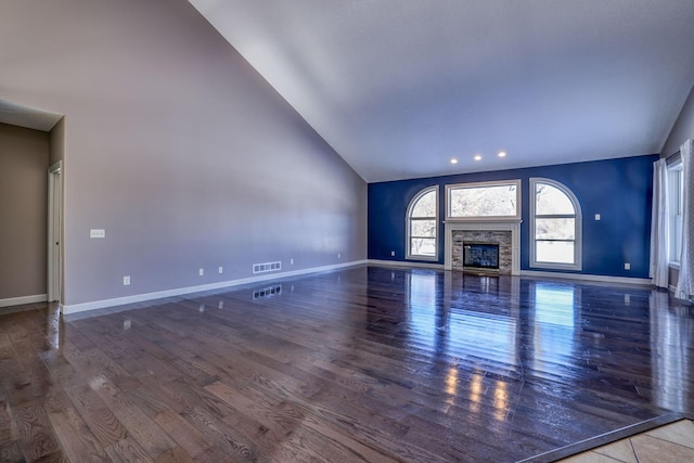 unfurnished living room with high vaulted ceiling, visible vents, wood finished floors, and a glass covered fireplace