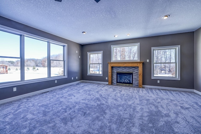 unfurnished living room featuring carpet floors, a fireplace, baseboards, and a textured ceiling