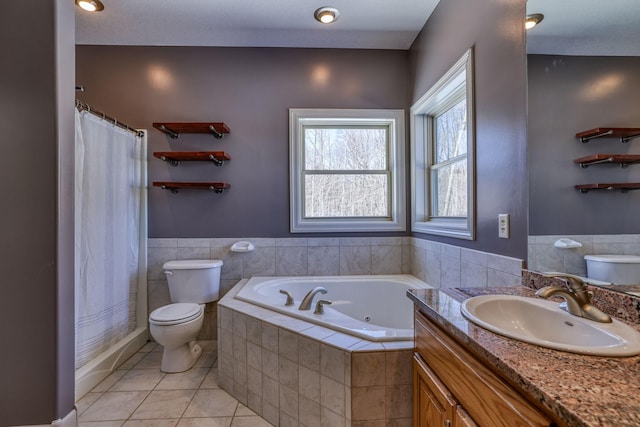 bathroom with a wainscoted wall, toilet, vanity, tile patterned flooring, and a whirlpool tub