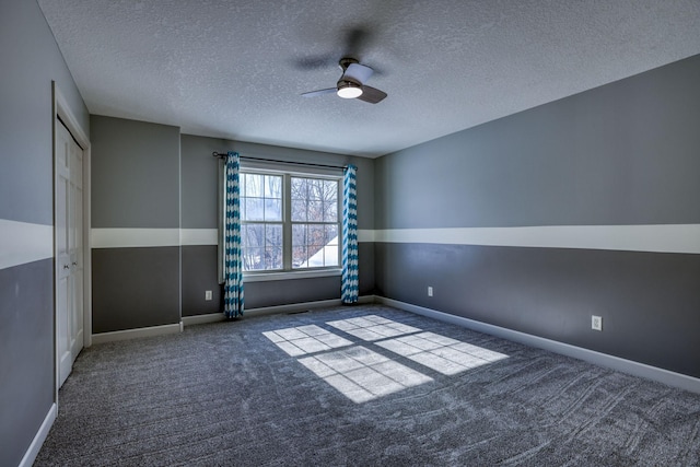 carpeted empty room featuring ceiling fan, a textured ceiling, and baseboards