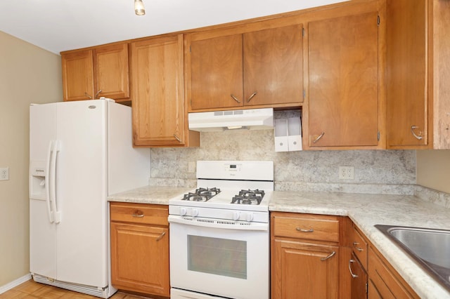 kitchen featuring backsplash, white appliances, and sink