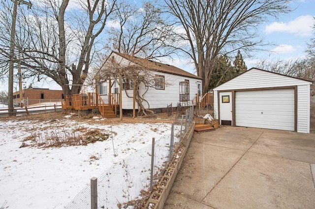 snowy yard with a garage, an outdoor structure, and a deck