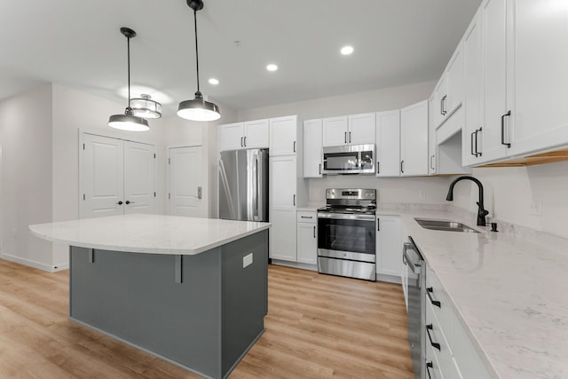 kitchen with pendant lighting, white cabinets, a kitchen island, stainless steel appliances, and sink