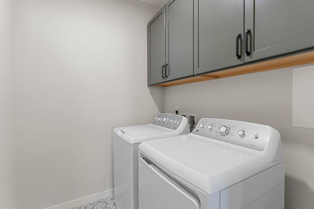 clothes washing area featuring cabinets and washer and clothes dryer