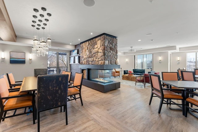 dining room with light hardwood / wood-style floors and a stone fireplace