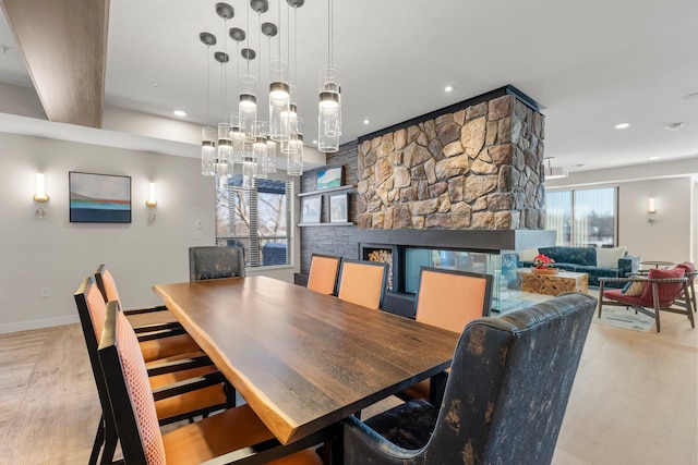 dining room featuring light hardwood / wood-style floors and a stone fireplace