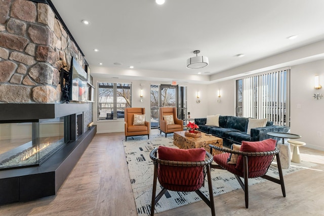 living room with light hardwood / wood-style flooring and a stone fireplace