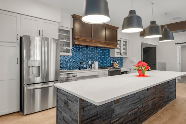 kitchen with pendant lighting, white cabinets, a center island, stainless steel appliances, and tasteful backsplash