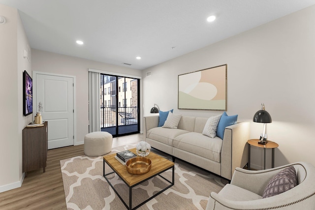 living room featuring light wood-style floors, visible vents, baseboards, and recessed lighting