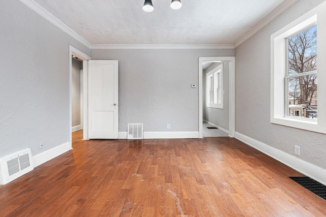 unfurnished room with a textured ceiling, crown molding, and wood-type flooring