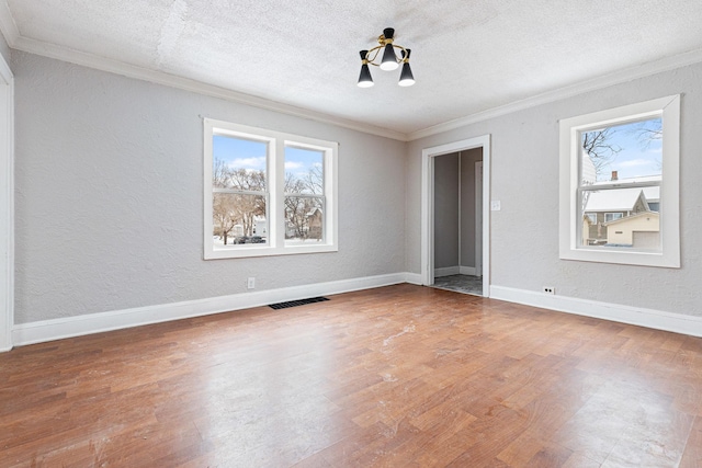 unfurnished bedroom with hardwood / wood-style floors, a textured ceiling, ornamental molding, and a notable chandelier