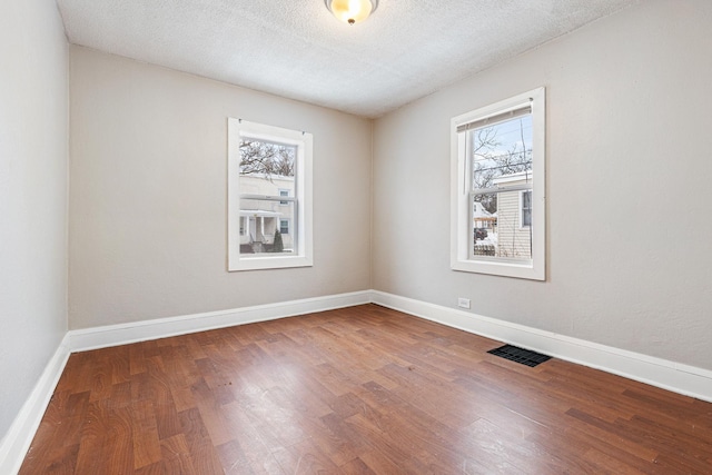 unfurnished room with hardwood / wood-style flooring and a textured ceiling