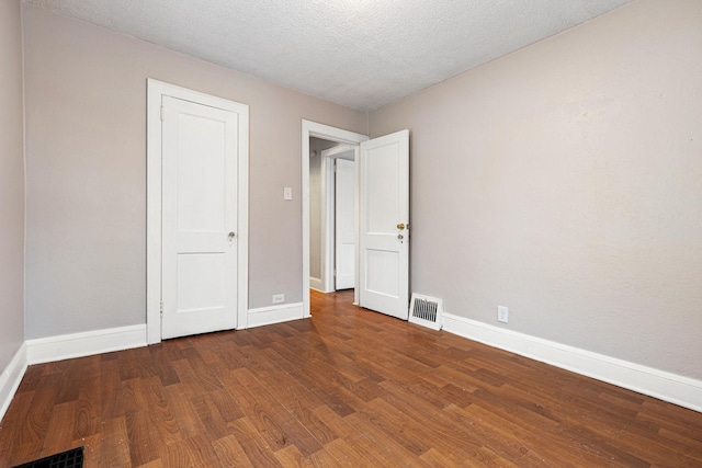 unfurnished bedroom with a textured ceiling and dark hardwood / wood-style flooring