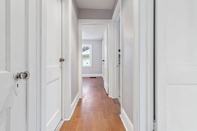 hall with wood-type flooring and a textured ceiling